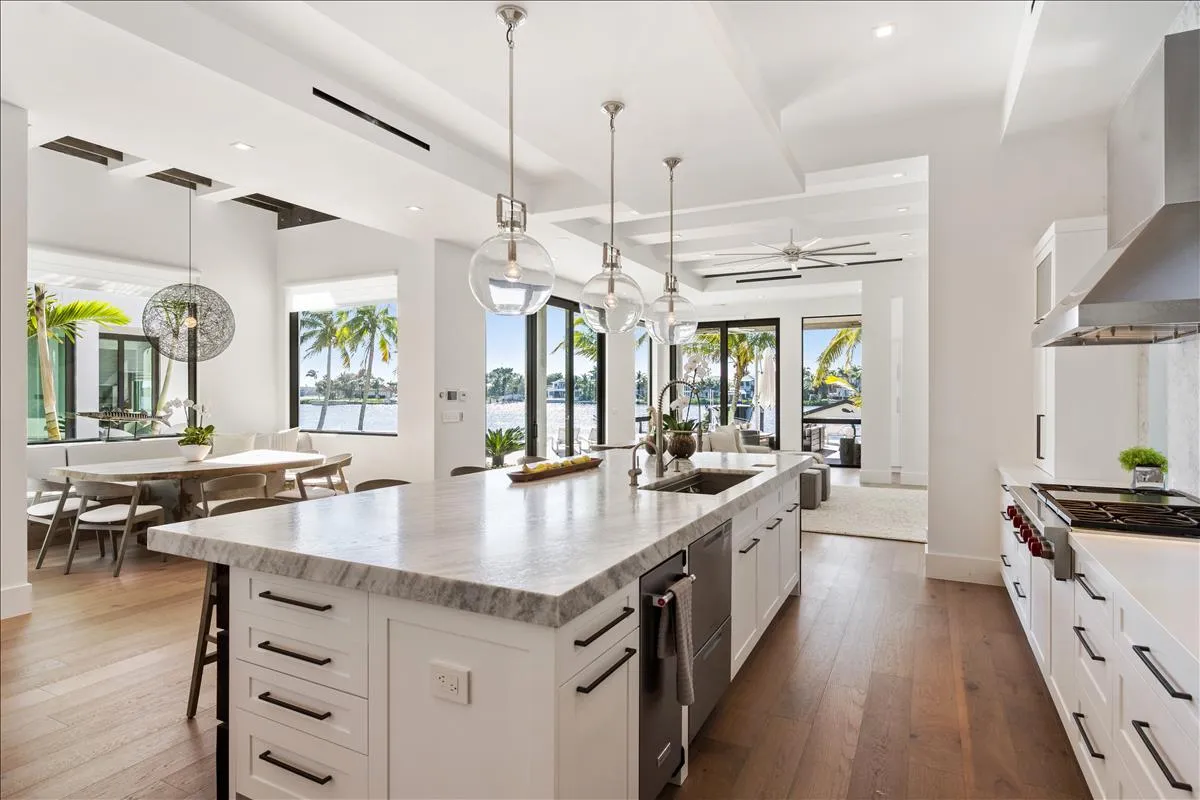 Chef's kitchen with marble island, pendant lights, and waterfront views
