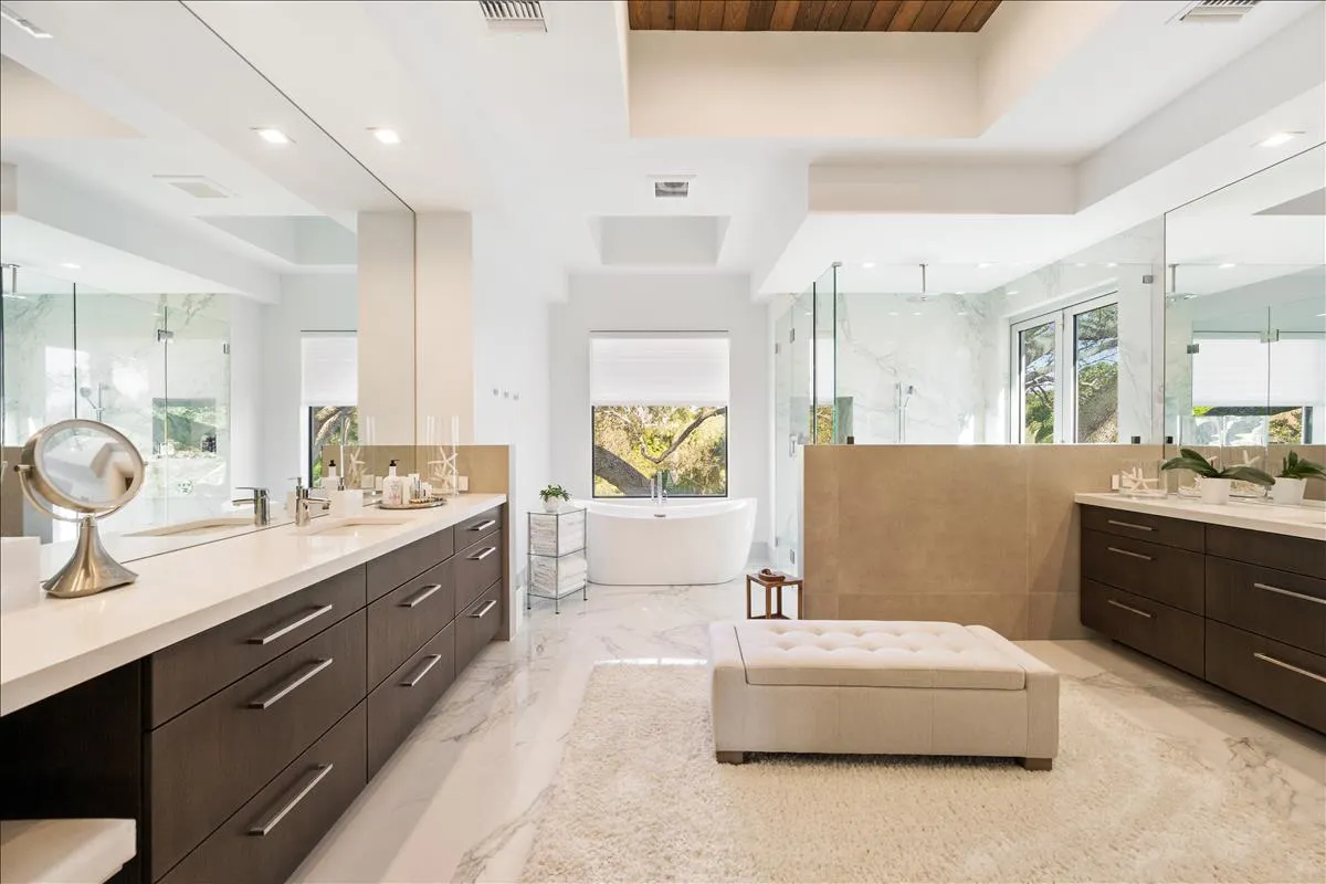 Master bath with dual vanities, freestanding tub, glass shower, and wood ceiling