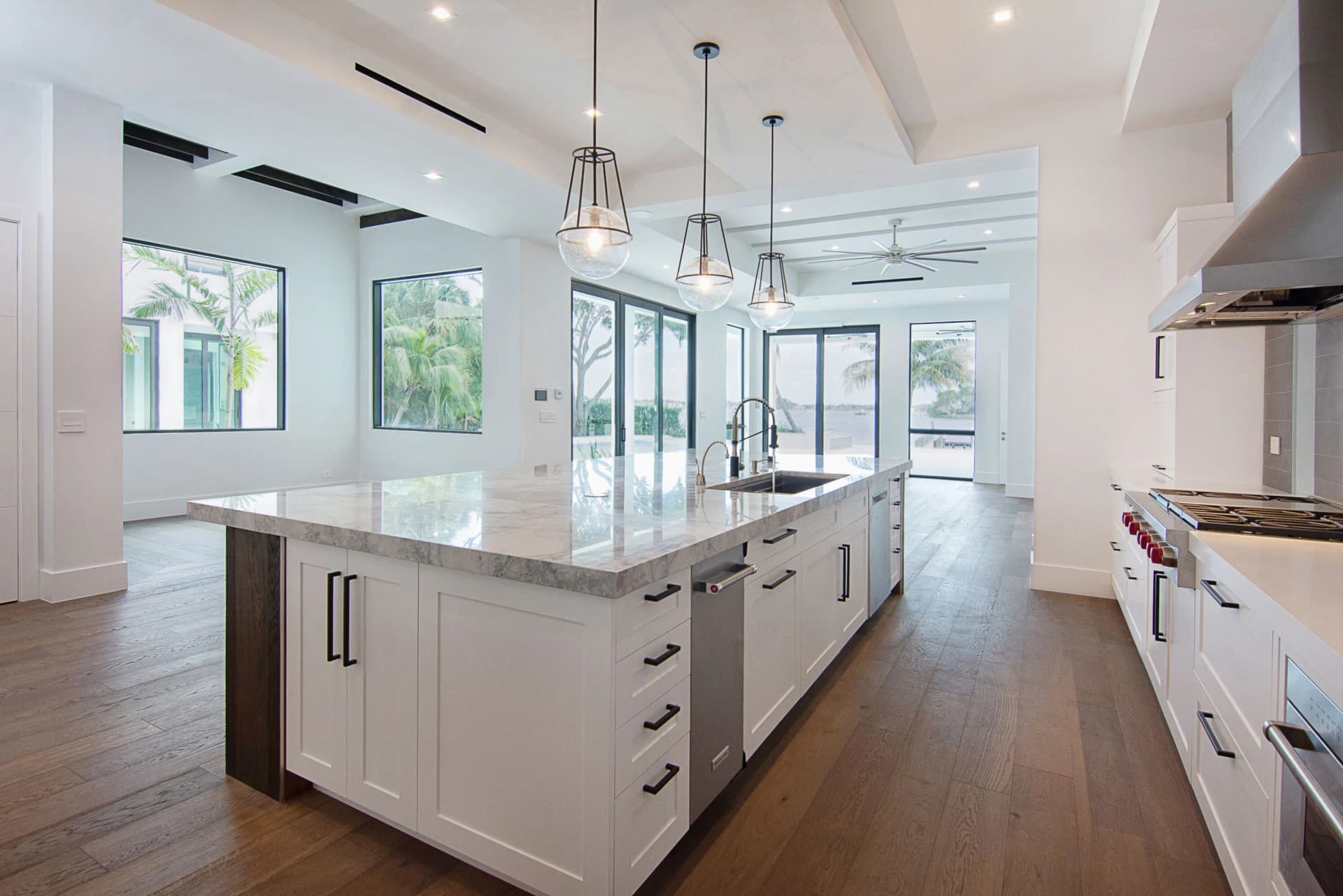 Kitchen with white shaker cabinets, marble island, glass pendants, and professional range