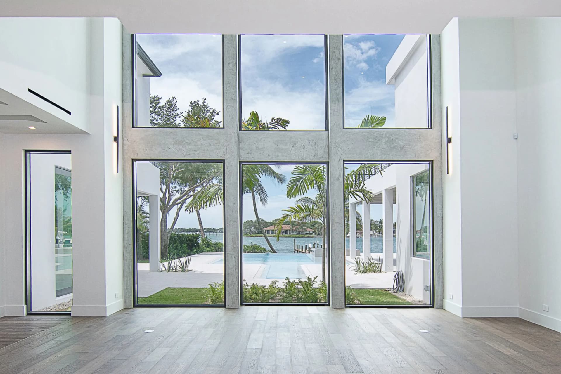 Double-height window wall with concrete mullions overlooking pool and waterfront