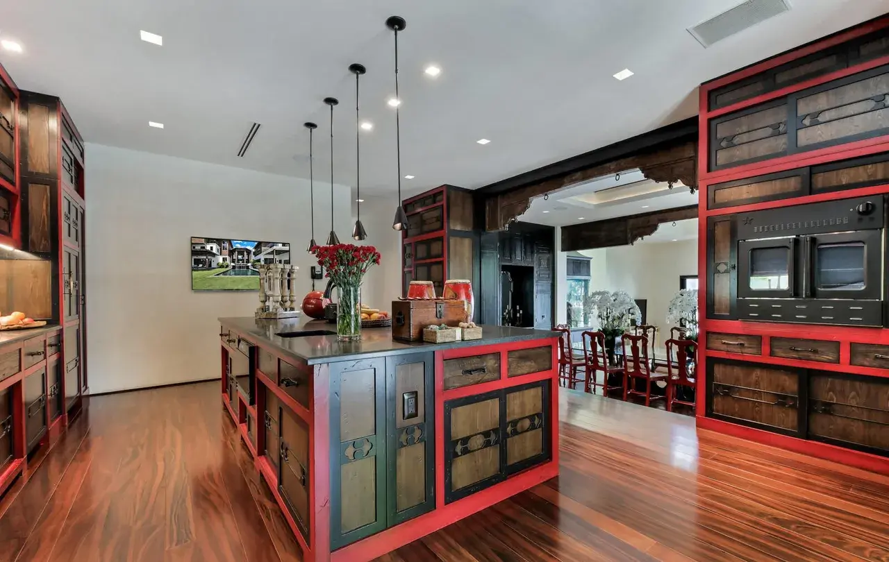 Kitchen with red and dark wood Asian cabinetry, stone island counter
