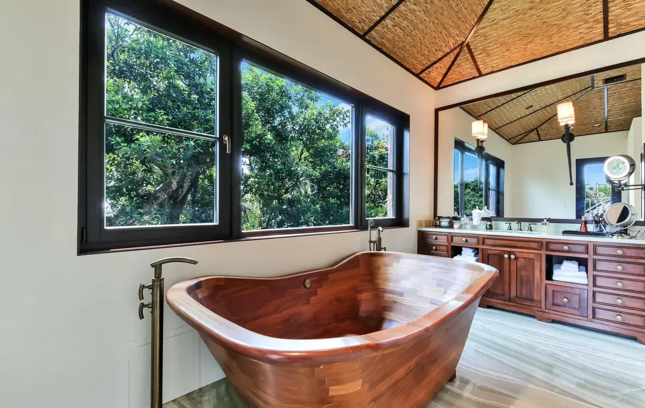 Master bath with wooden soaking tub, thatched ceiling, and marble vanity