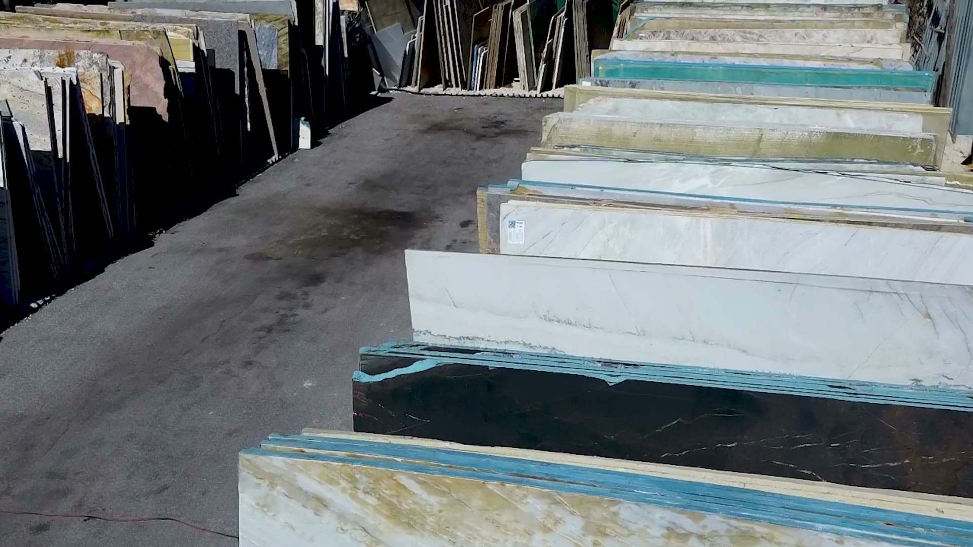 Rows of full stone slabs standing outdoors in the GMFI slab yard in Boynton Beach